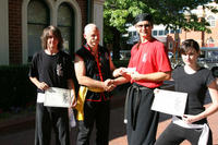 Master Hardy presents a cheques for 4 months' training to Sifu Bellchambers, with the successful scholarship recipients - Sam and Eva.